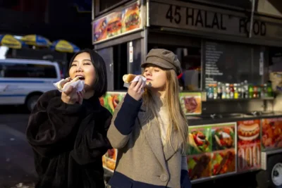 Two women eating food truck hotdog in New York City - NYC Food Tour